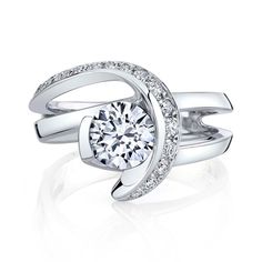 A fun fact about the Vision engagement ring is that it is the only Mark Schneider bridal style without a European squared shank. That being said, we can still make it with one if you would prefer. This ring is accented with 18 diamonds for a total weight of 0.245 carats. Your center stone is semi-bezel set at the same height as the accent diamonds that swoop around to hold it in place. The matching wedding band is set with 15 diamonds, for a total weight of 0.15 carats and it is unique because i Modern Rings With Brilliant Cushion Cut, Modern Rings With Brilliant And Cushion Cut, Asscher Cut Tension Setting Promise Ring, Modern Moissanite Asscher Cut Wedding Ring, Modern Diamond Ring With Center Stone, Modern Moissanite Wedding Ring With Center Stone, Fine Jewelry Bypass Ring With Tension Setting For Promise, Asscher Cut Promise Ring With Tension Setting, Modern Solitaire Asscher Cut Ring