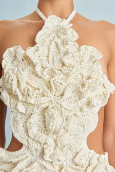 the back of a woman's white dress with crocheted flowers on it