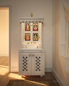 a white cabinet with pictures on the wall above it