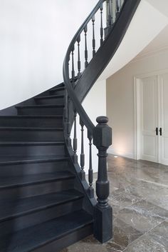 a black stair case next to a white door in a room with marble flooring