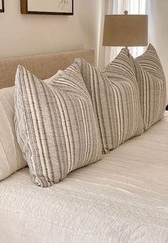 a bed with three pillows on top of it and two framed pictures above the headboard