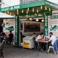 people sitting at tables in front of a restaurant