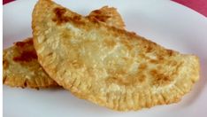 two fried pastries on a white plate next to a pink tablecloth and fork