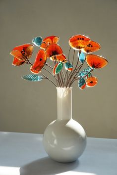 a white vase filled with orange flowers on top of a table