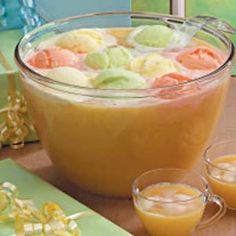 two glasses filled with liquid sitting on top of a table next to some fruit and vegetables