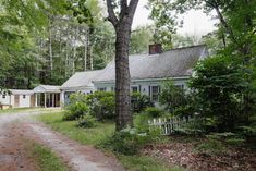 a house in the woods with a dirt path leading to it