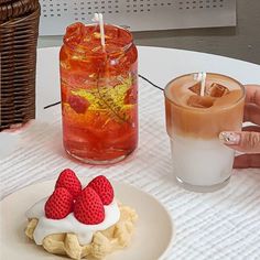 two strawberries are placed on top of a dessert with whipped cream and a drink