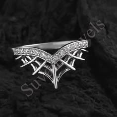 a white gold ring with diamonds in the shape of an eagle on top of rocks