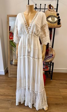 a white dress is displayed on a mannequin in front of a wooden floor