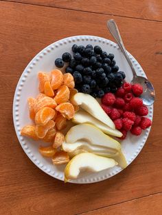 a white plate topped with fruit next to a spoon