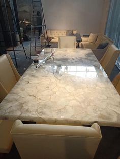 a marble dining table surrounded by beige chairs