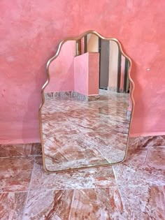 a mirror sitting on top of a marble floor next to a pink wall with stripes