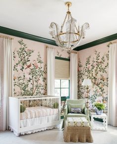 a baby's room decorated in pink and green with floral wallpaper, chandelier and crib