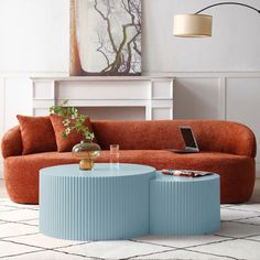 a living room with an orange couch and blue coffee table in the middle, along with a white rug on the floor