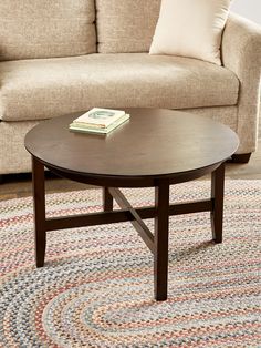 a coffee table with a book on it in front of a couch and rugs