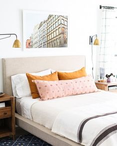 a bedroom with a bed, nightstands and pictures on the wall above it in orange