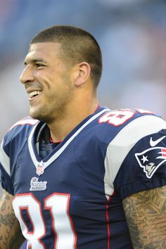 a close up of a football player with tattoos on his arm and chest, smiling at the camera