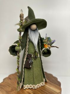 a green wizard doll with white hair and beard holding a wand on a wooden board