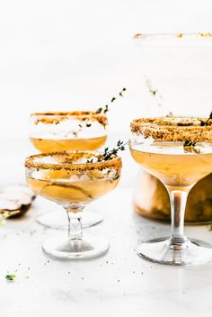 three glasses filled with champagne and garnished with herbs on the rims, sitting next to each other