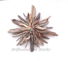 a star made out of driftwood with a green bead sits on a white surface