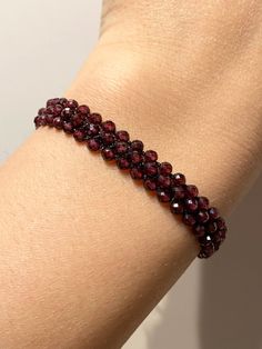 Add a touch of elegance to your outfit with this handmade natural red garnet bracelet.  The faceted garnet stones are hand-knitted onto a black rope to create a unique macrame design.  This bracelet is 16 cm in size, but can be adjusted to your desired size upon request. Not only does this bracelet add a pop of color to your look, it also carries significant meaning.  Garnet is known for symbolizing faith, love, devotion, and trust, as well as balancing out emotional states and promoting passion Luxury Handmade Garnet Jewelry, Elegant Ruby Gemstone Beads Bracelets, Elegant Ruby Beaded Bracelets With Gemstones, Elegant Ruby Gemstone Beaded Bracelets, Elegant Burgundy Bracelets As Gifts, Elegant Red Faceted Beaded Bracelets, Handmade Elegant Red Crystal Bracelet, Elegant Handmade Red Crystal Bracelet, Adjustable Garnet Gemstone Bracelet