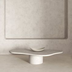 a white table with a bowl on it in front of a square shaped wall mounted mirror