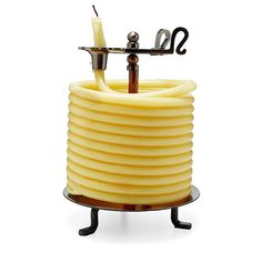 a candle holder made out of yellow wax and metal wire with a hook on the top