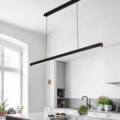 a kitchen with white cabinets and an island in front of a window that has potted plants on it