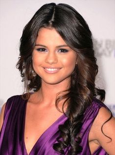 a woman in a purple dress smiling for the camera