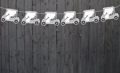 a string of paper cut out of cars hanging from a line on a wooden fence