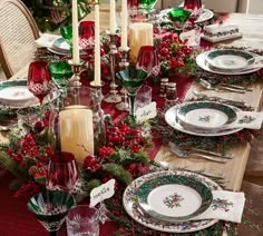 a christmas table setting with candles, plates and napkins on top of the table