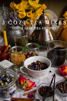 the cover of 3 cozy tea mixes looseed out on a table with flowers and herbs