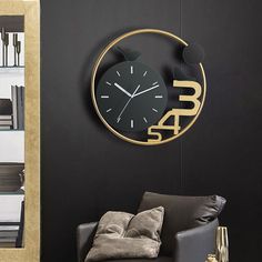 a black and gold clock is on the wall next to a gray chair in a living room