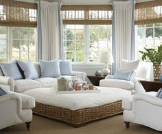 a living room filled with white furniture and blue pillows on top of it's covers