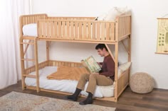 a man sitting on top of a bunk bed next to a white pillow and rug