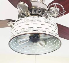 a ceiling fan that is hanging from the ceiling in front of a white wall with a logo on it