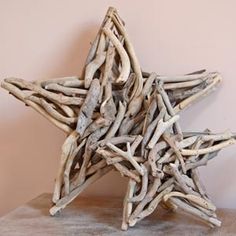 a star made out of driftwood sitting on top of a wooden table next to a pink wall