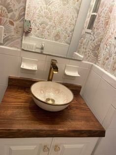 a bathroom sink sitting on top of a wooden counter next to a white cabinet and mirror