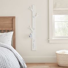 a bed room with a neatly made bed and a tall growth ruler on the wall