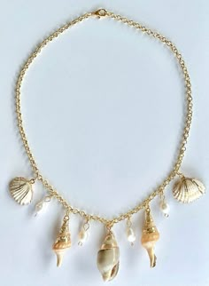 The Seashell and Freshwater Pearl Necklace  is a dazzling piece that captures the serene beauty of summer's coastal magic. Perfect for adding a touch of seaside elegance to any outfit, this necklace features a stunning combination of seashells with gold accents and freshwater pearl charms. The centerpiece of this captivating necklace is a collection of seashells delicately accented with gold, each one evoking the timeless allure of the ocean. These seashells are accompanied by lustrous freshwater pearls, creating a harmonious blend of textures and elegance. Strung on a delicate gold chain, the Ocean Jewel Charm Necklace radiates a sense of graceful summer elegance, making it an exquisite accessory for any occasion. Whether you're enjoying a day at the beach, attending a casual summer outin Luxury Gold Shell Necklace With Pearl Charm, Shell-shaped Ocean-inspired Jewelry With Starfish Charm, Ocean-inspired Jewelry With Starfish Charm And Shell Shape, Ocean-inspired Shell Jewelry With Starfish Charm, Beach Shell Charm Necklace With Pearl, Elegant Starfish Charm Jewelry For Vacation, Ocean-inspired Pearl Charm Necklace For Vacation, Ocean-inspired Pearl Necklace For Beach, Beach Jewelry With Shell-shaped Lobster Clasp