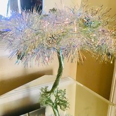 a glass vase filled with a tree covered in tinsel and sprinkles