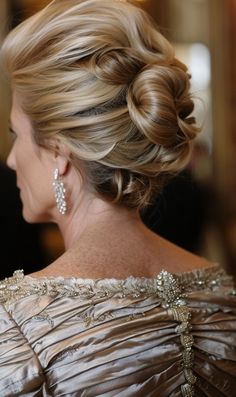 a woman with blonde hair in a formal updo and earrings on her head, looking off to the side