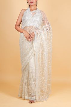 The Net designer Saree with sequin work in off white is a masterpiece of elegance. The delicate net fabric is adorned with intricate sequin work, creating a stunning and luxurious look. Perfect for special occasions, this saree will make you feel like a high-end fashion icon. Net designer Saree with sequin work - off white Saree comes with a blouse piece. Fall and pico done. Fully stitched blouse shown in pictures is optional and can be purchased seperately from our blouses and croptops section. For saree video please connect with us on whatsapp @469-937-0606 Ready to be shipped in USA from San Diego, California. All pictures are original pictures. Colors may slightly vary due to pic resolution. Bollywood Style White Pre-draped Saree With Pearl Embroidery, Festive Off White Blouse Piece With Sheer Dupatta, White Georgette Pre-draped Saree With Pearl Embroidery, White Pre-draped Saree With Resham Embroidery For Wedding, Festive White Pre-draped Saree With Intricate Embroidery, Elegant Sequined Organza Pre-draped Saree, White Bollywood Pre-draped Saree For Reception, Elegant Organza Pre-draped Saree With Sequins, Designer Pre-draped Off White Saree With Sheer Dupatta