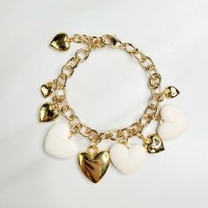 Vintage hearts are the focal point of this love filled bracelet. An assortment of gold plated hearts and matte ivory hearts play along the edge, perfect as a gift for someone you love. Handmade in the United States, a matching necklace and earring set are available. Features: - Gold Plated Vintage Hearts - Matte Ivory Vintage Hearts - Gold Plated Mixed Cable Chain - Lobster Claw Clasp - Extension - Handmade in the United States Dimensions: - Length: 7.5" - Extension: 1" - Total Length: 8.5" Gold-tone Metal Jewelry With Heart Charm, Valentine's Day Gold-plated Jewelry With Dangling Charms, Elegant White Charm Bracelet With Heart Charm, White Heart-shaped Jewelry Gift For Her, White Heart-shaped Jewelry With Heart Charm, White Heart Shaped Jewelry With Heart Beads, Gold Dangle Jewelry With Heart Beads, White Heart-shaped Metal Charm Bracelet, Elegant White Heart Charm Bracelet