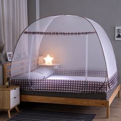 a bed with a mosquito net over it and a night stand in front of it