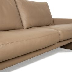 a tan leather couch with two pillows on it's back and one arm facing the camera