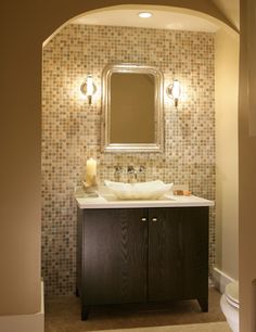 an archway leads into a bathroom with a sink and mirror on the wall above it