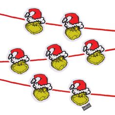 the grin face stickers are attached to red string with white and green santa's hats on them