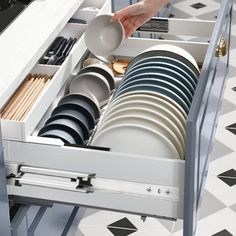 a person is reaching for dishes in a drawer