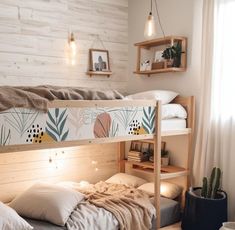 a bunk bed with pillows and blankets in a bedroom next to a potted plant